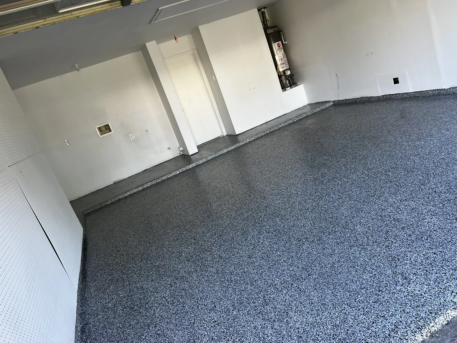 Garage floor in grey flake, white slat wall and water heater along the back